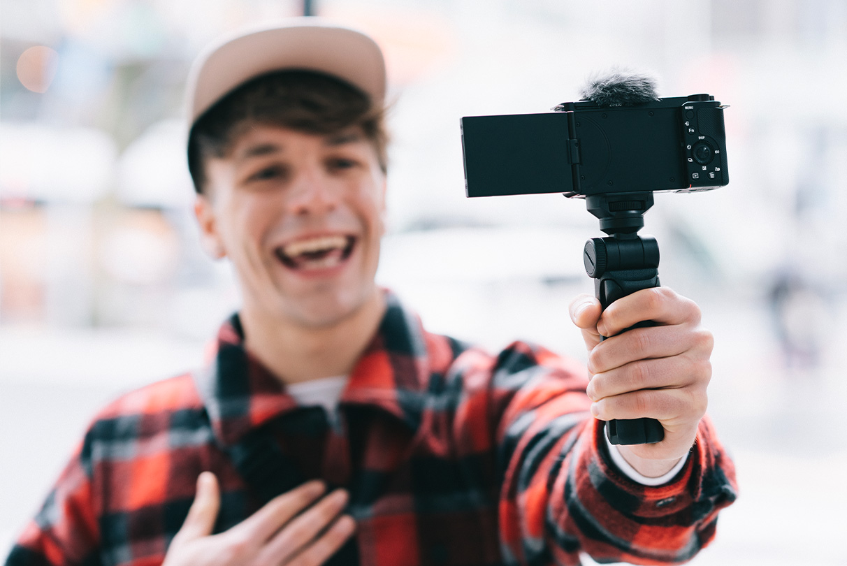 Image of person filming himself using ZV-E10 with grip attached