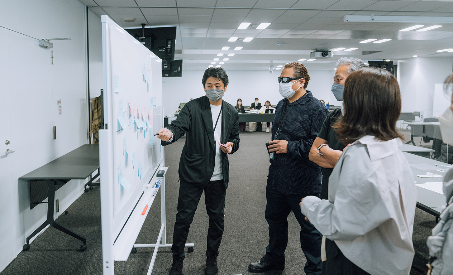 Employees gather in front of a whiteboard and having a conversation