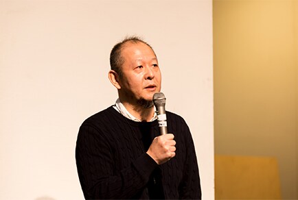 Photo of Yutaka Hasegawa speaking on stage