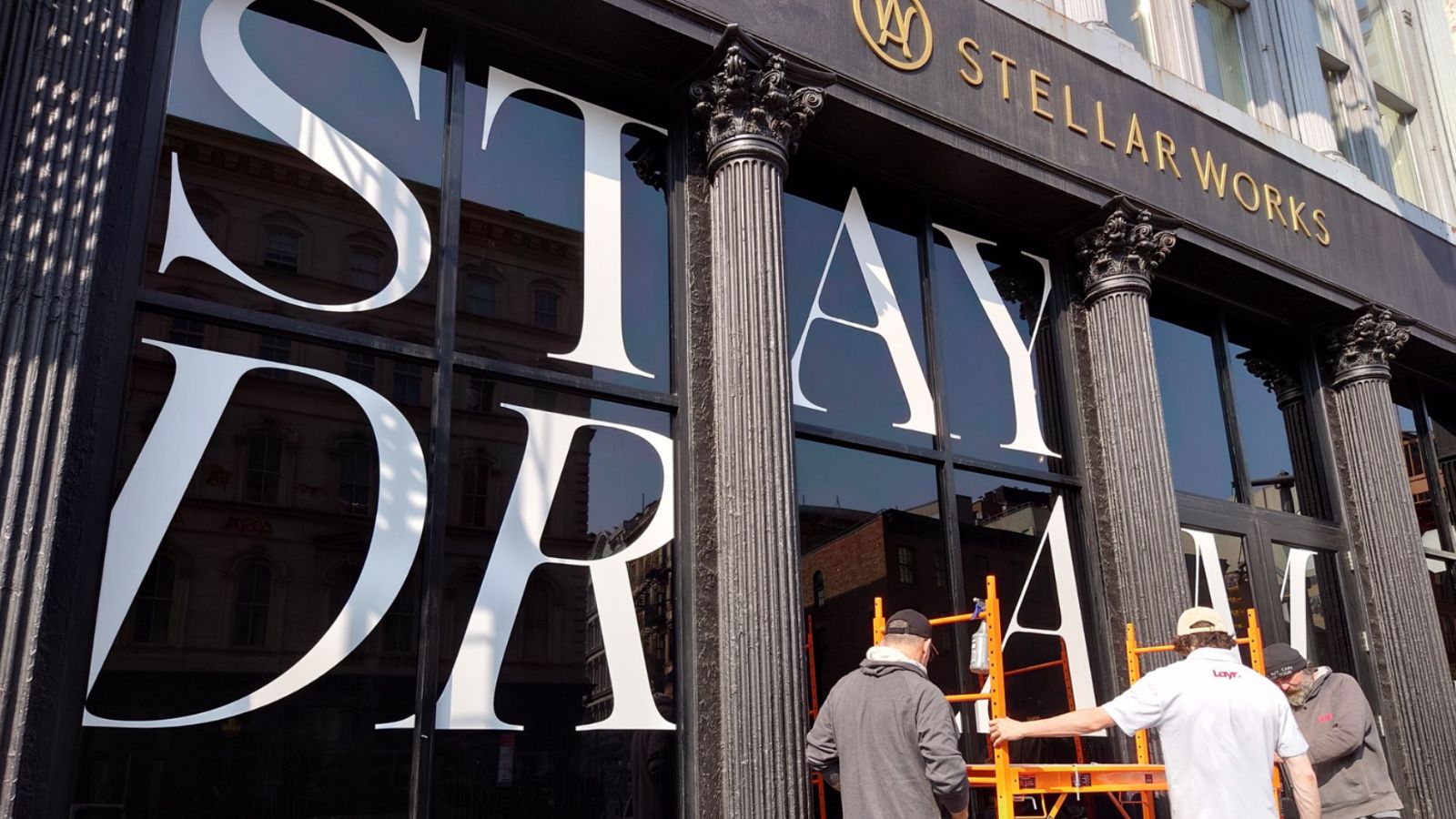 Supplier applying large ‘STAYDREAM’ vinyl letters to building windows