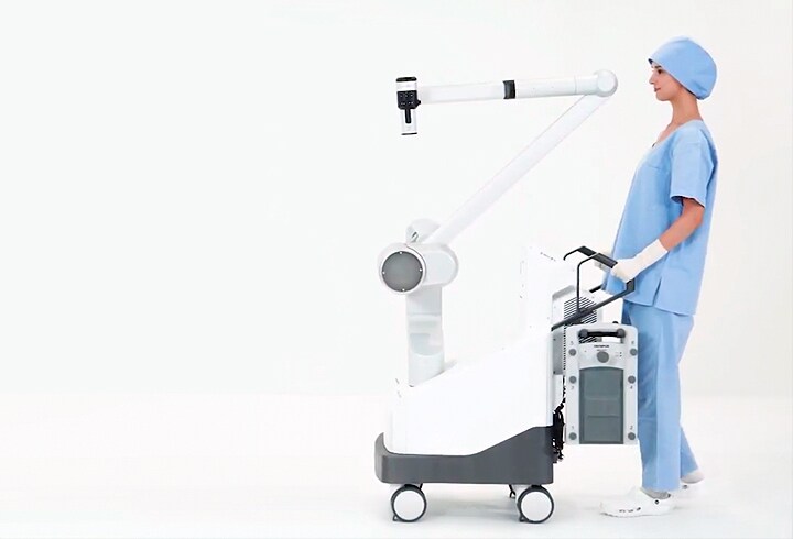 Photo of a member of the surgical team moving the surgical microscope system