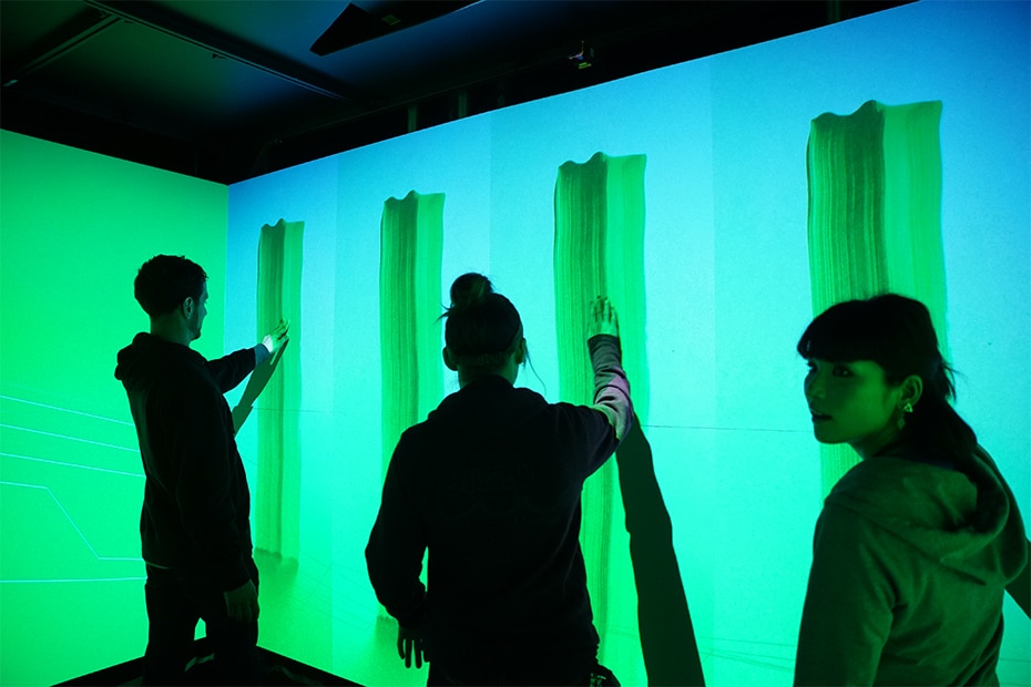 Photo of visitors enjoying the Warp Square where green graphic is projected