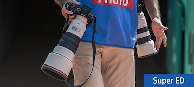 Usage image showing male photographer carrying two cameras with telephoto lenses