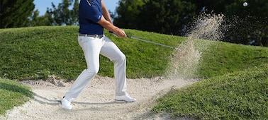 Example image of a golfer performing a bunker shot, moments after the club struck the ball