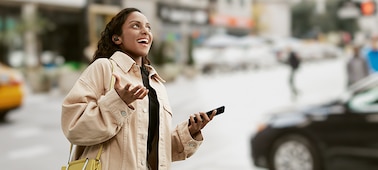 Woman wearing LinkBuds S while walking in a town and talking on her smartphone