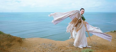 Example image showing woman in period costume with coastline in background