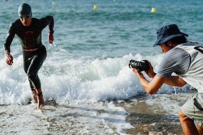 Usage image of a man holding the camera to shoot a triathlete running out of the sea