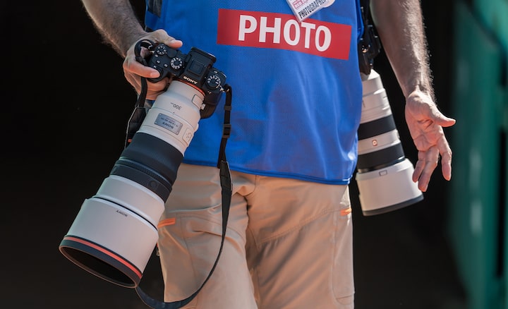 Usage image showing male photographer carrying twocameras with telephoto lenses