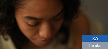 A portrait captured from above, showcasing a black woman with long lashes looking downwards in a softly lit interior.