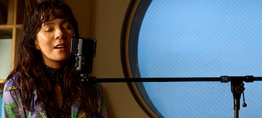 Usage image of a woman singing into a microphone attached to a boom-arm stand