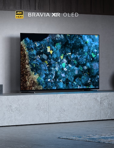 A80L Series BRAVIA TV in living room on a large gray plinth with blue crystals on screen and 4K HDR, BRAVIA XR and OLED logos