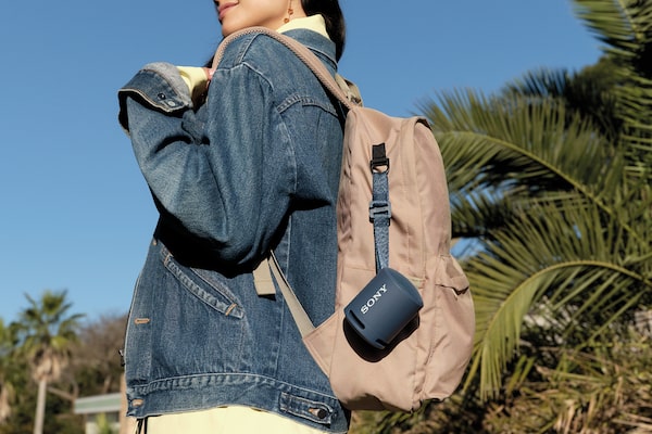 Image of the XB13 EXTRA BASS(TM) Portable Wireless Speaker attached to a young woman's backpack.