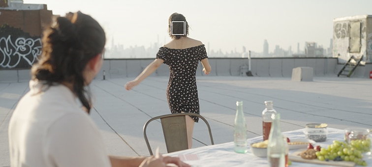 Image of a woman walking away and a woman sitting and looking at her