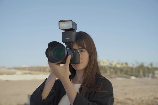 Usage image of a photographer holding the camera with an external flash attached