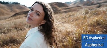 A portrait of a female looking back at this lens in a wide field covered with plume grass. Her hair and the plume grass are shine besides the focus is on her left eye