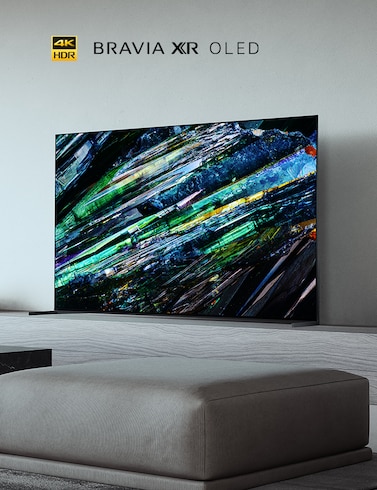 A95L Series BRAVIA TV in living room on a large gray wooden plinth with green, blue and black artwork on screen and 4K HDR, BRAVIA XR and OLED logos