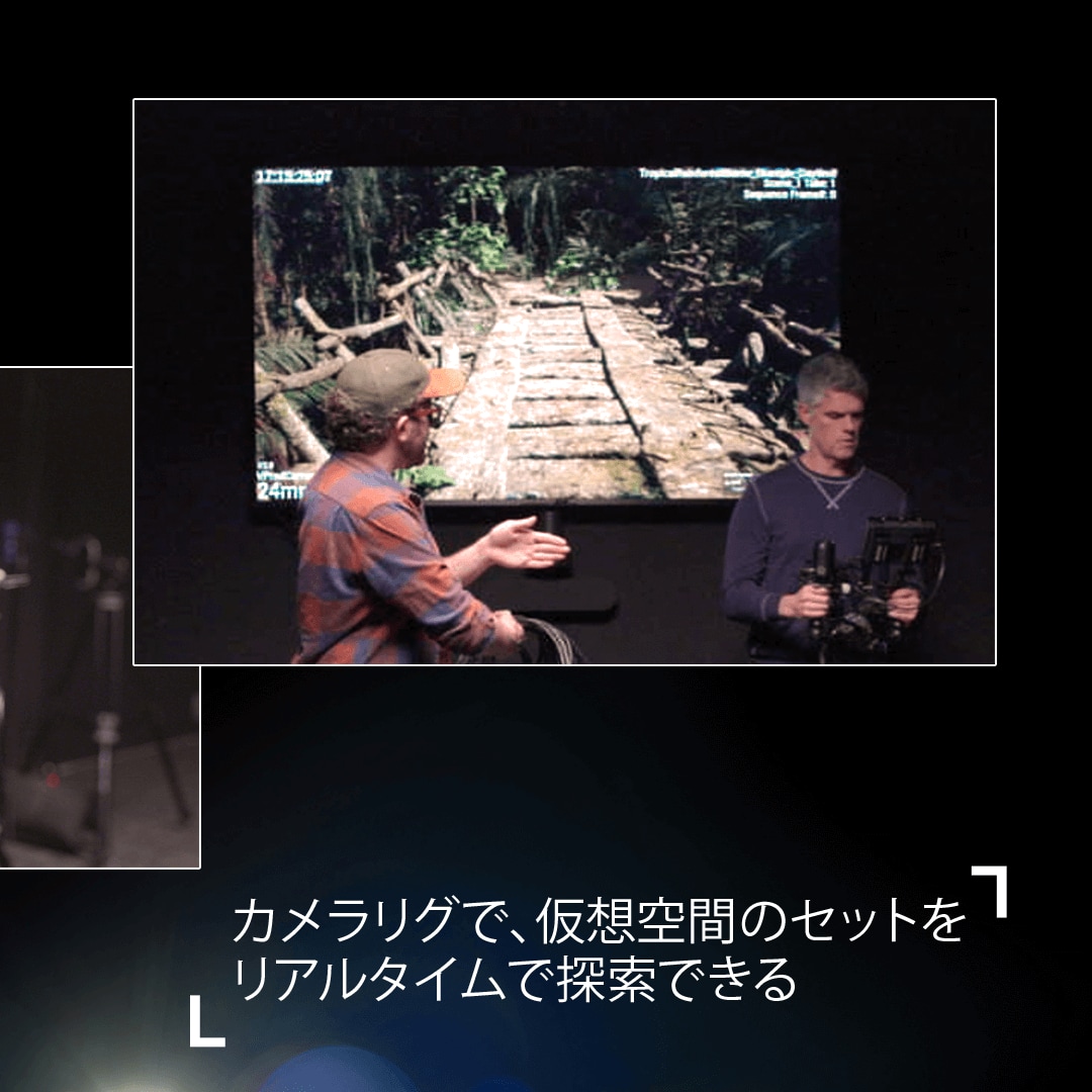 大きなビデオスクリーンの前で話す2人の男性。一人はジェスチャーをしていて、もう一人はバーチャルカメラリグを持っている。ビデオスクリーンにはジャングルの中に掛かる橋のバーチャルセットが映し出されている。テキストで、 'カメラリグで、仮想空間のセットをリアルタイムで探索できる 'と書かれている。